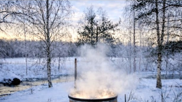 A snow-covered outdoor area with a wood-burning stove, benches, and a fence. - Riverfront Cottageee (Äänekoski)