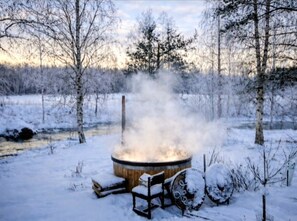 A snow-covered outdoor area with a wood-burning stove, benches, and a fence. - Riverfront Cottageee (Äänekoski)
