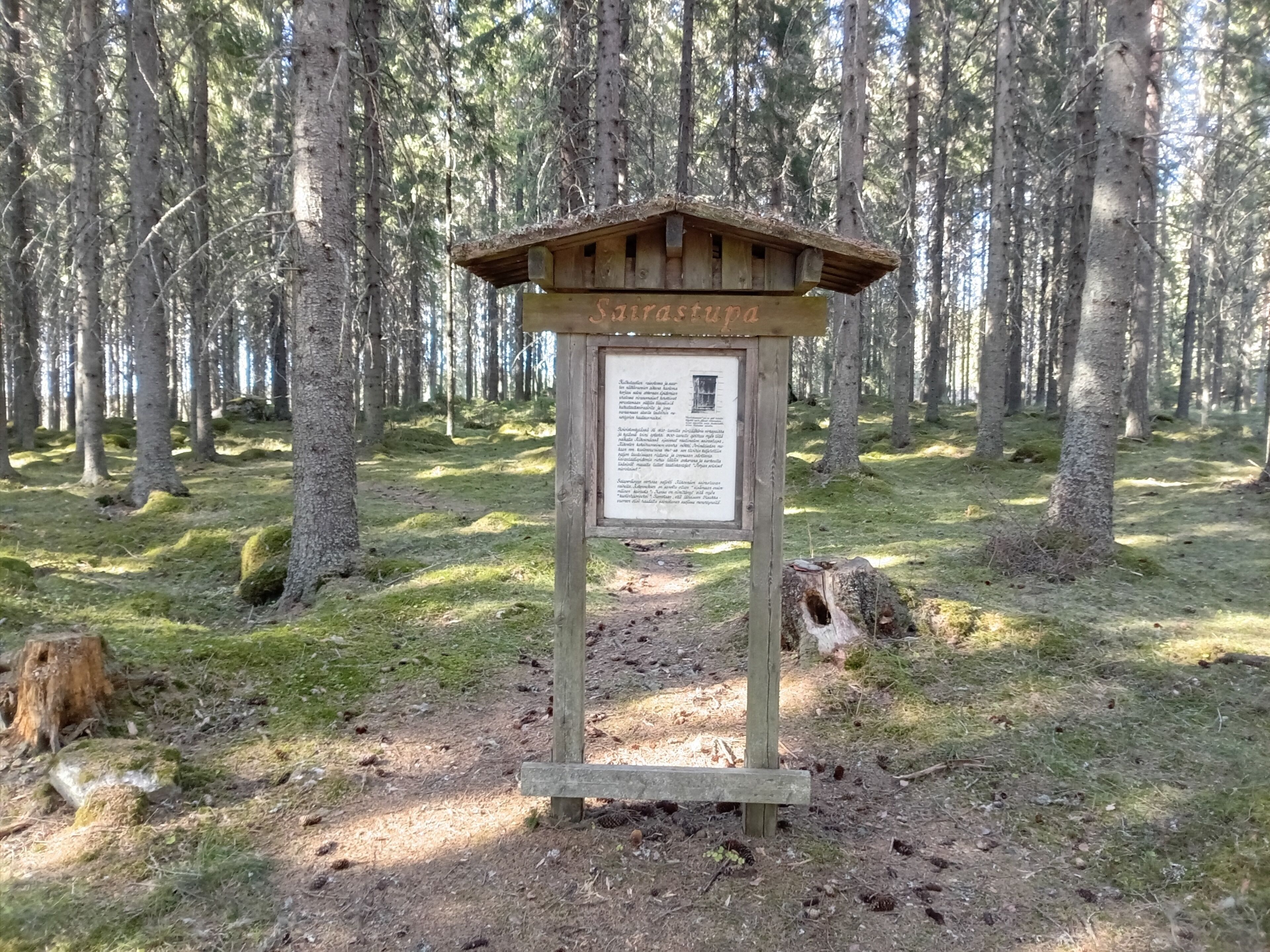 A wooden signpost with text in a forested area.
