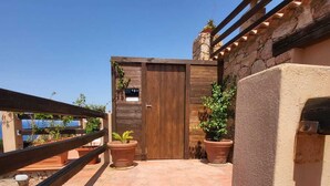 A rooftop terrace with terracotta tiles, wooden pergolas, and potted plants.