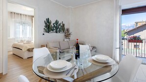 Un coin repas avec une table en verre, des assiettes blanches et une bouteille de vin.