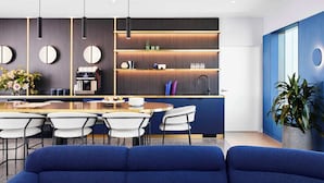 A modern kitchen with a central island, bar stools, and a seating area with a blue sofa.