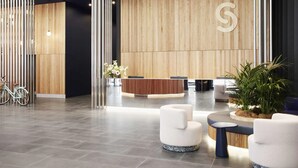 A modern reception area with a wooden wall, a reception desk, and seating arrangements.