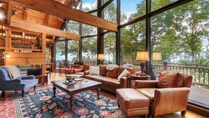 A spacious living area with a large window, wooden ceiling, and a cozy seating arrangement.