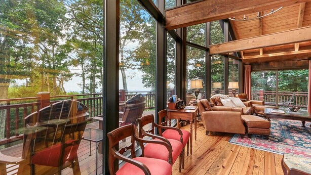 A spacious indoor area with large windows, wooden deck, and comfortable seating.