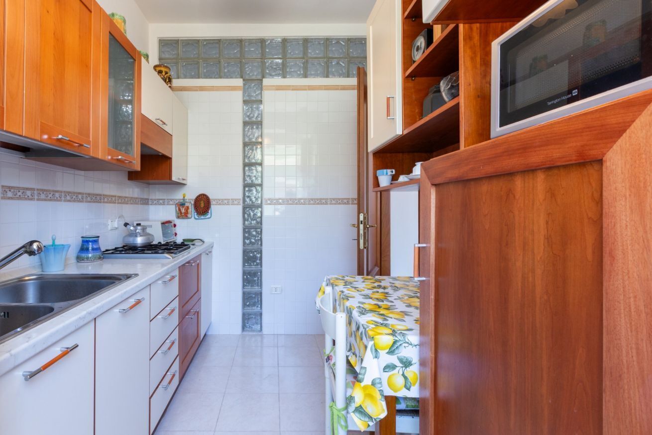 A compact kitchen with wooden cabinets, a stainless steel sink, a stove, and a microwave.
