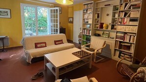 A cozy living room with a sofa, a coffee table, a bookshelf, and a chair. - House for rent in Oléron (La Rémigeasse) 100 m from the beach (6 people) (Dolus-d'Oléron)