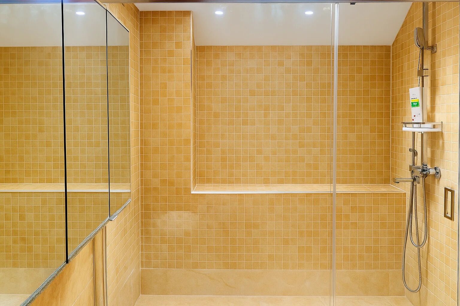 A modern bathroom with a glass shower enclosure, tiled walls, and a built-in bench.
