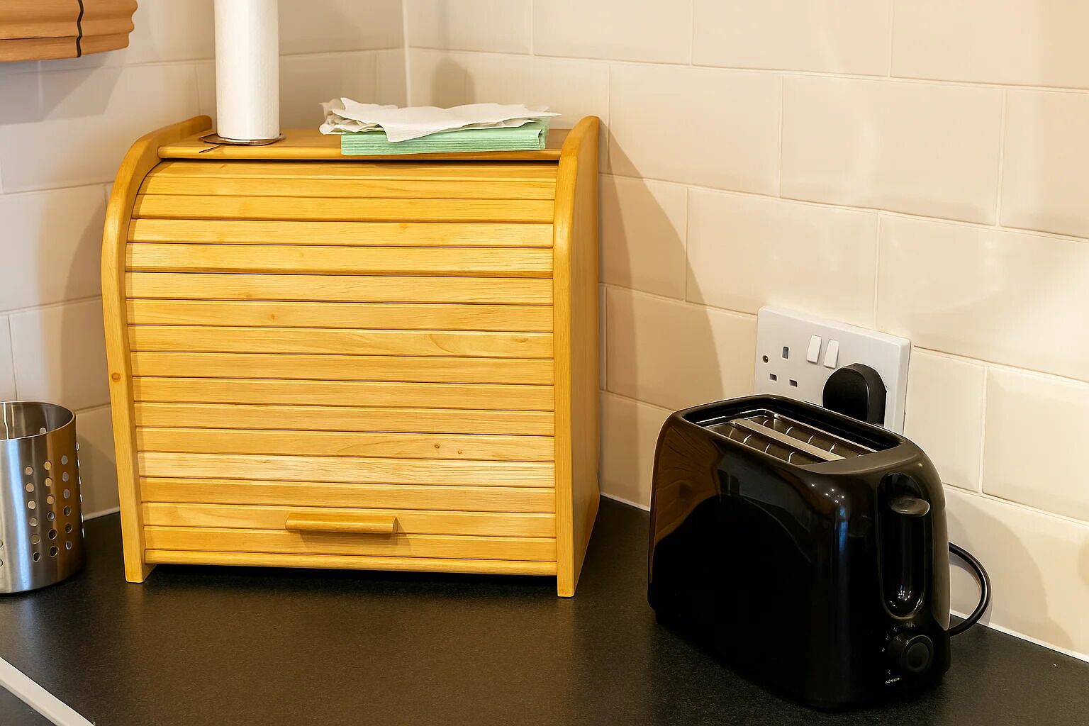 A kitchen with a wooden drawer unit, a black toaster, and a white electrical outlet on the wall.