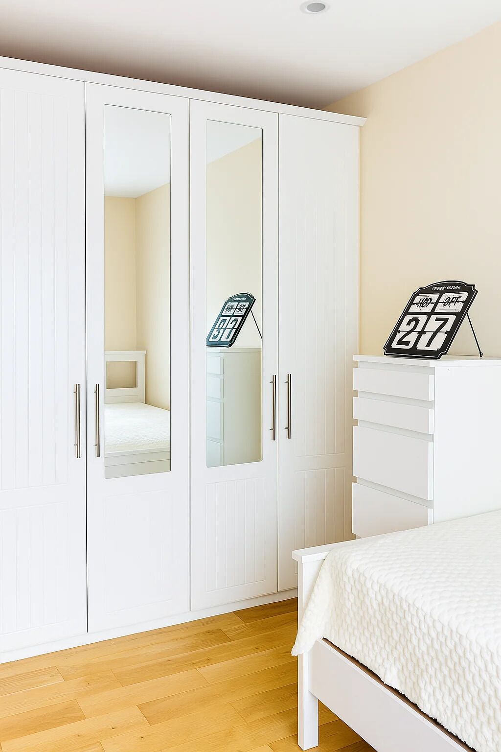 Une chambre à coucher comprenant un lit, une armoire aux portes miroir et une commode.