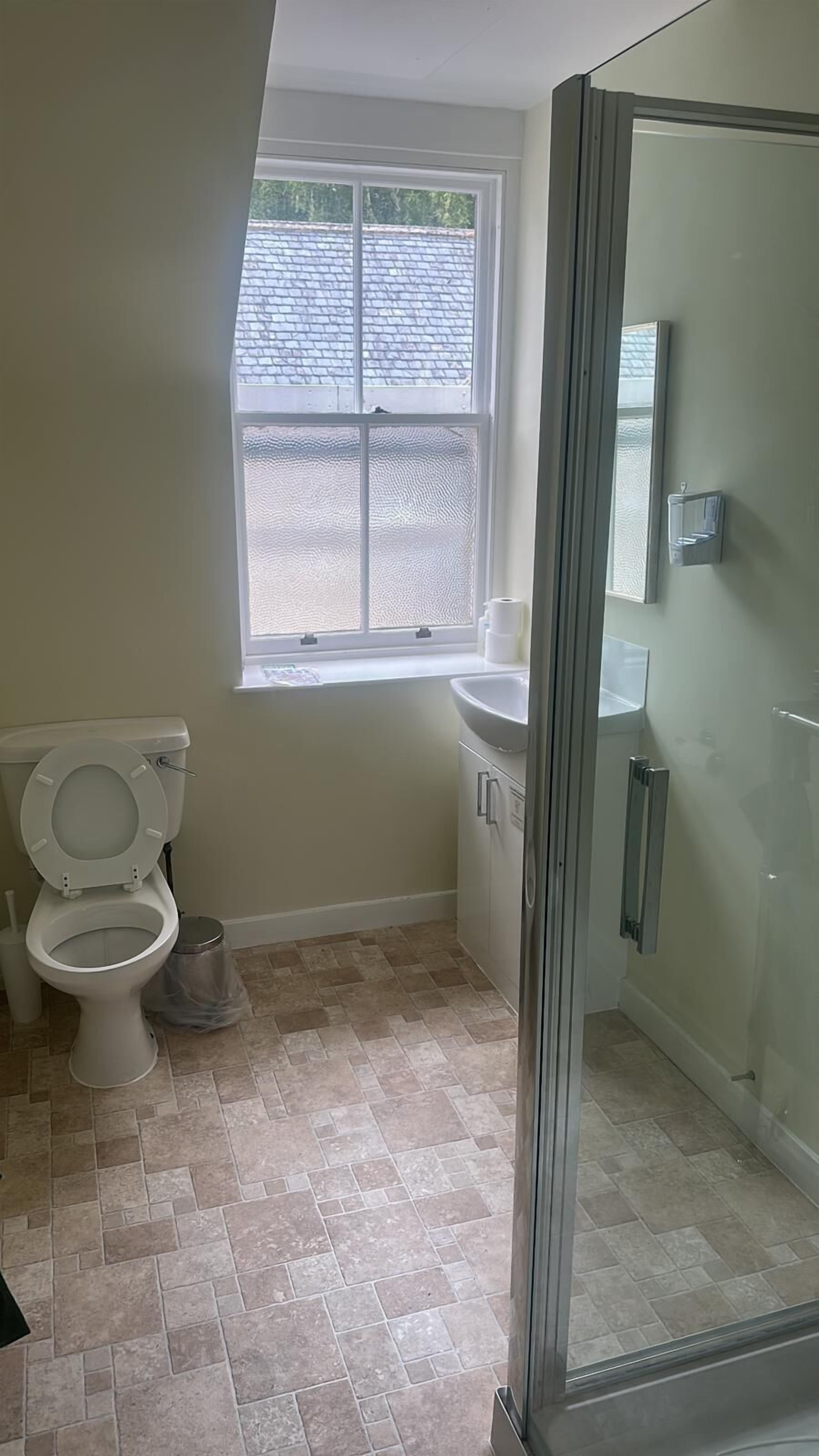 Une salle de bain avec des toilettes, un lavabo et une douche.