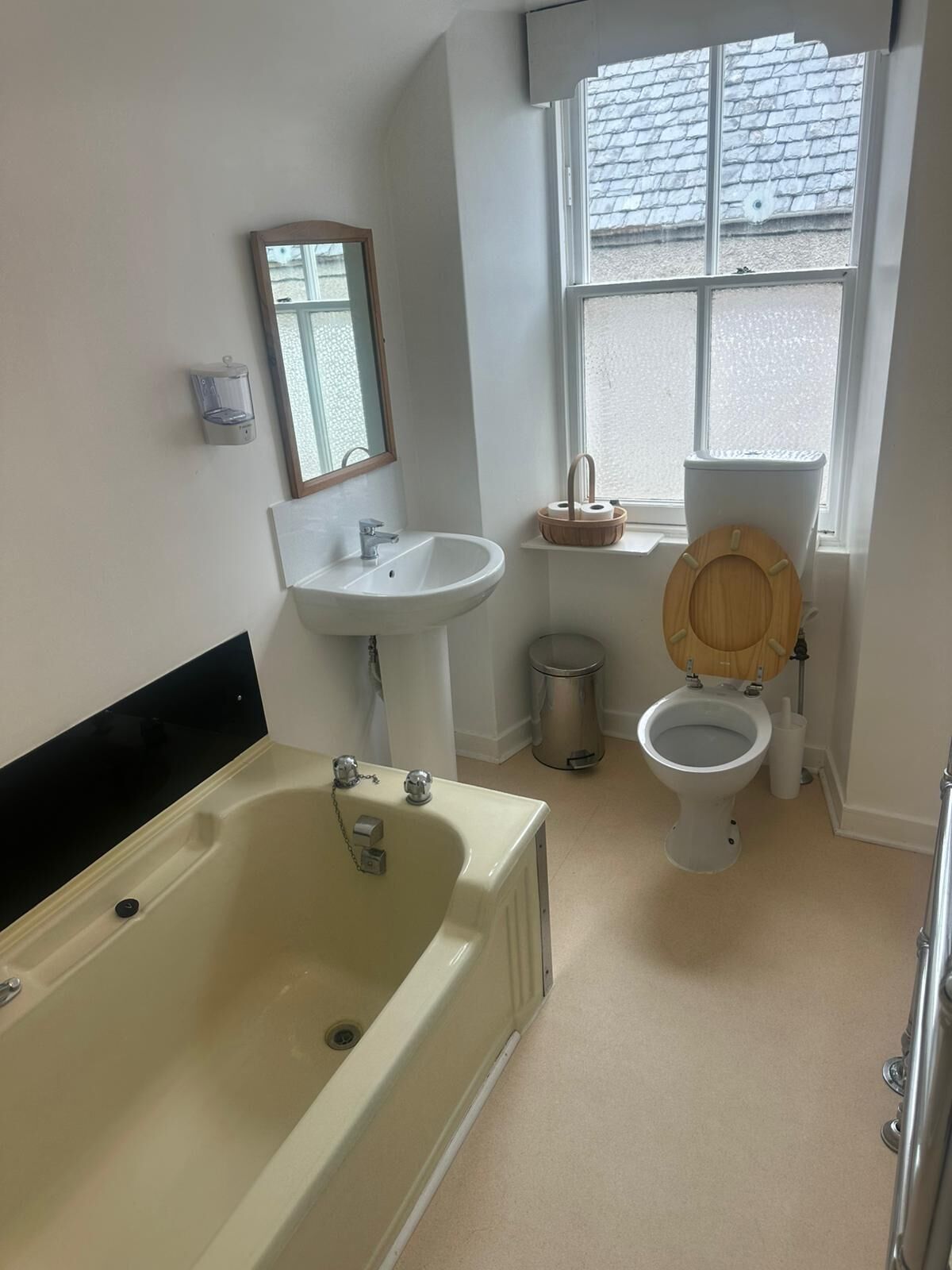 Un baño con bañera, lavamanos, inodoro y ventana.