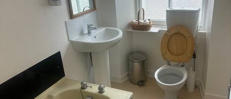 Ein Badezimmer mit Badewanne, Waschbecken, Toilette und Fenster.