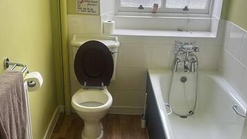 Un baño con inodoro, bañera y ventana.