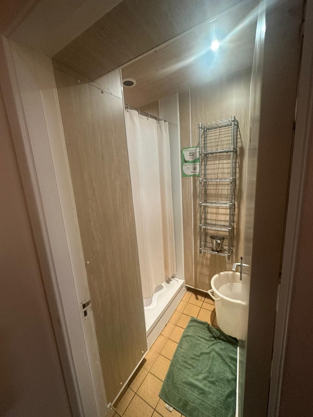 A bathroom with a shower, a sink, and a metal rack.