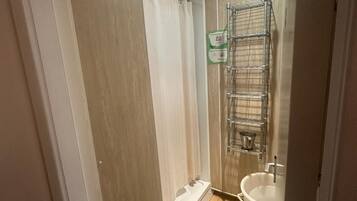 A bathroom with a shower, a sink, and a metal rack.