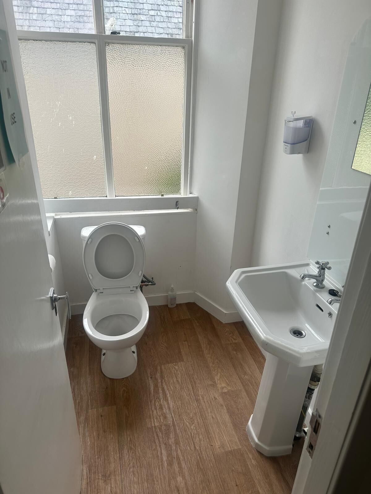 A small, clean bathroom with a toilet, sink, and window.