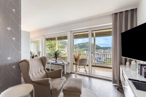 A modern living room with a sofa, armchair, and a flat-screen TV.