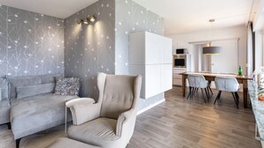 A modern living room with a sofa, armchair, and dining area with a table and chairs. - Apartment '7' with Shared Garden and Wi-Fi (Willingen (Upland))
