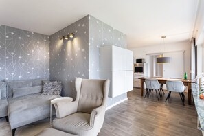 Un salon moderne comprenant un canapé, un fauteuil et un coin repas avec une table et des chaises.