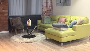 A modern living room with a green sofa, a glass coffee table, and a fluffy rug. - New Apartment - Sleeps 4 - Parking - City Centre (Bradford)
