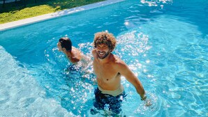 A swimming pool with clear blue water and a tiled edge.