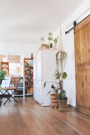 A kitchen with wooden flooring, a white refrigerator, and a wooden sliding door.