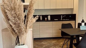 A modern kitchen with light wood cabinets, a black countertop, and a dining area with a black table and chairs. - Lovely 2-bedroom apartment with terrace & parking (Izola)