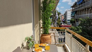 Un balcón con una mesa lista para el desayuno, una silla y una planta en maceta.