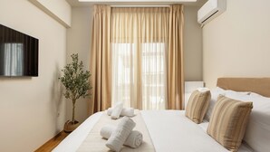 Una habitación de hotel con una cama, cortinas, una planta en maceta y un televisor de pantalla plana.