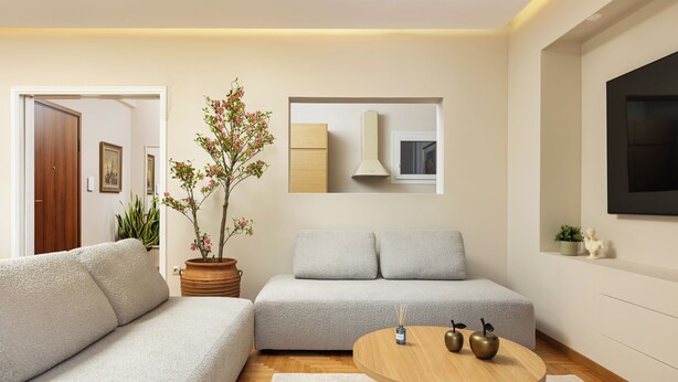 Una sala moderna con un sofá, una mesa de centro redonda de madera y una planta en maceta.