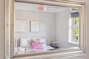 A bedroom with a bed, a bedside table, a window, and two wall-mounted artworks. - 2BR Apt Near Windsor Castle Free Park By Tempstay (Windsor)