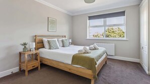 Ein Schlafzimmer mit einem Holzbett, einem Nachttisch, einer Heizung und einem Fenster mit Blick.