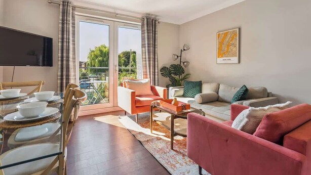 Ein modernes Wohnzimmer mit einer Couch, Sesseln, einem Couchtisch und einem Fernseher.