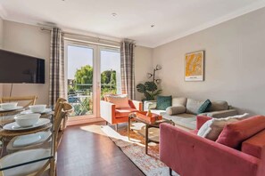 A modern living room with a sofa, armchairs, a coffee table, and a TV. - 2BR Apt Near Windsor Castle Free Park By Tempstay (Windsor)