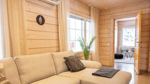 A cozy room with a beige sectional sofa, a small table, and a chair. - Villa Pyry (Sotkamo)