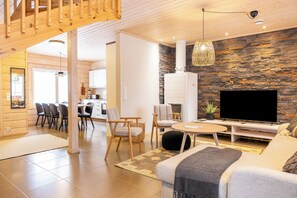 Ein modernes Wohnzimmer mit Steinwand, Flachbildfernseher und Holzboden.
