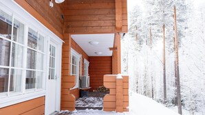 A wooden building with a covered porch and a snow-covered landscape. - Villa Pyry (Sotkamo)