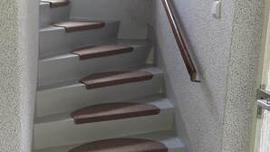 Una escalera con barandillas de madera y peldaños alfombrados que conduce a una plataforma.