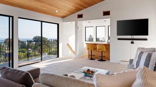 A modern living room with a large window, a flat-screen TV, and a dining area with yellow chairs. - Casual La Jolla Gem , Views & Space for 10 (San Diego)
