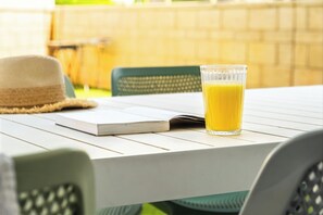 A table with a glass of orange juice, a notebook, and a straw hat.