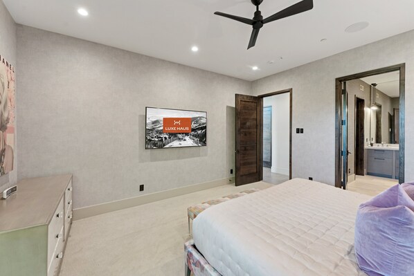Un dormitorio moderno con cama, cómoda, ventilador de techo y un cuadro en la pared.