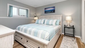 A bedroom with a bed, a nightstand, a window with curtains, a painting on the wall, and a lamp. - Three Ridges 64 With Wintergreen Advantage (Wintergreen)