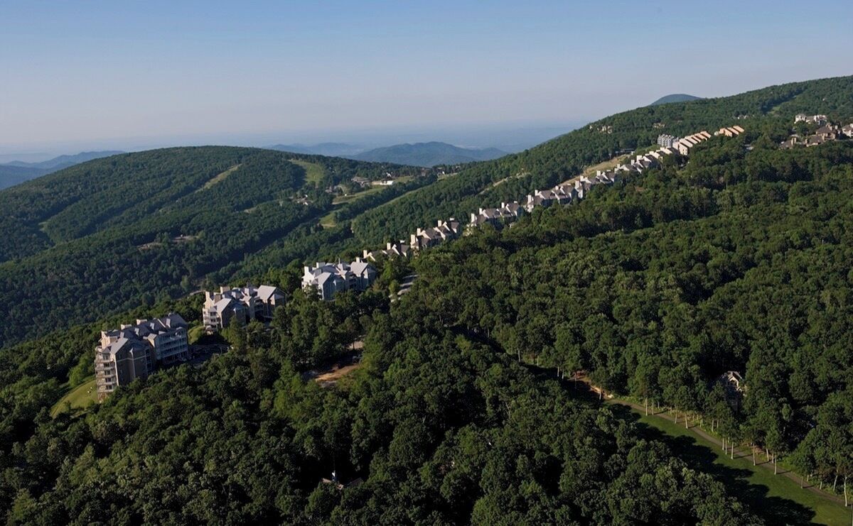 A resort with multiple buildings nestled in a forested hillside, offering panoramic views of the surrounding landscape.