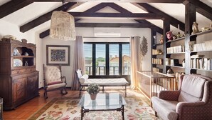Um quarto aconchegante com teto de madeira, um banco, um sofá, uma mesa de centro e uma estante de livros.