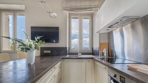 A modern kitchen with a large window, built-in oven, and a flat-screen TV. - Charming 2-Bed Appartment in the heart of Mougins with AC, near Cannes (Mougins)