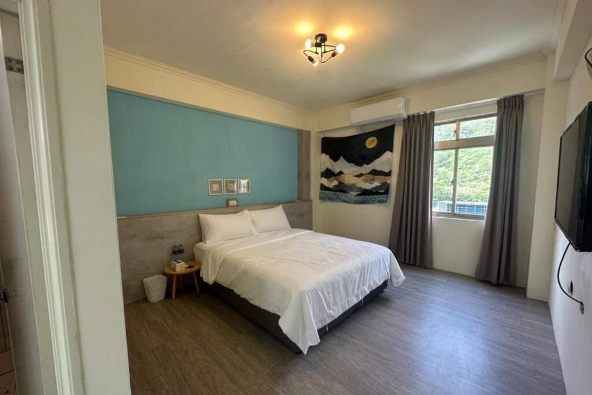 A bedroom with a bed, a night sky tapestry, a television, and a window with curtains.