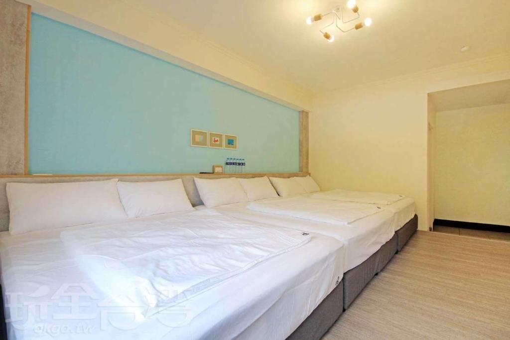 A large bed with white linens in a room with light blue walls and a wooden headboard.