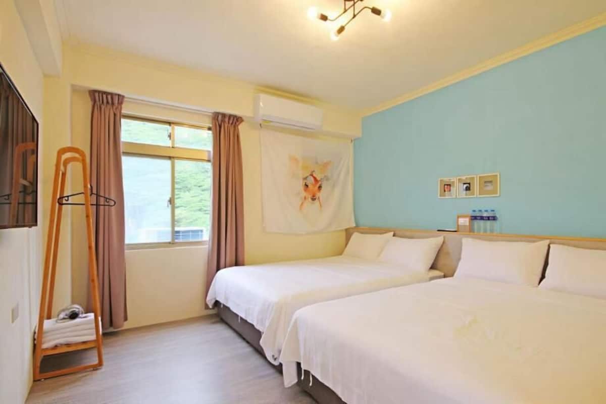 A hotel room with two beds, a window with curtains, a wall-mounted air conditioner, and a ceiling light fixture.