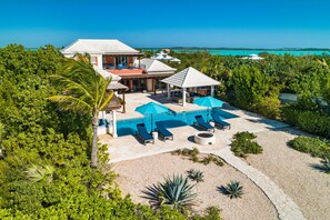 A resort with a pool area, lounge chairs, and a view of the ocean. - Villa La Percha With 4 Bedrooms and 4 5 Bathrooms (Providenciales)